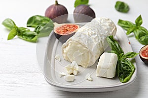 Delicious goat cheese with basil and figs on white wooden table