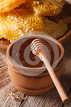 Delicious golden honey in a wooden bowl with a stick