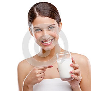 Delicious and good for you. Studio portrait of an attractive young woman pointing to the glass of milk shes holding.