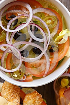 Delicious Greek salad served in recyclable paper plate for take away. Healthy fast food served in Mediterranean cafe