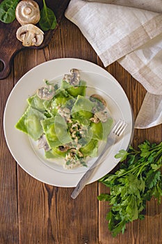 Delicious green dumplings with spinach dough stuffed with cheese with champignon sauce. Italian Cuisine.