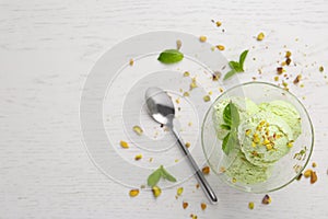 Delicious green ice cream served in dessert bowl on white wooden table, top view