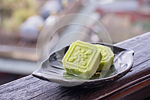 Delicious green mung bean cake with black tea plate on wooden railing of a teahouse in Taiwan with beautiful landscape in