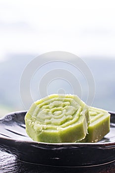 Delicious green mung bean cake with black tea plate on wooden railing of a teahouse in Taiwan with beautiful landscape in