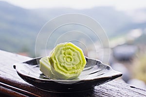 Delicious green mung bean cake with black tea plate on wooden railing of a teahouse in Taiwan with beautiful landscape in