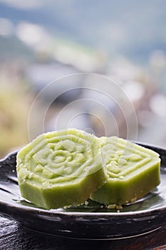 Delicious green mung bean cake with black tea plate on wooden railing of a teahouse in Taiwan with beautiful landscape in