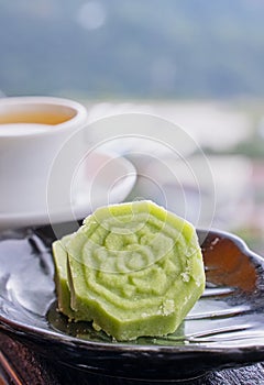 Delicious green mung bean cake with black tea plate on wooden railing of a teahouse in Taiwan with beautiful landscape in
