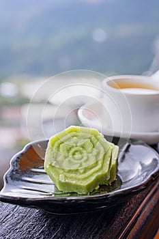 Delicious green mung bean cake with black tea plate on wooden railing of a teahouse in Taiwan with beautiful landscape in