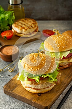 Delicious grilled burgers, hamburger sandwich with cutlet of chicken meat, melted cheese, tomatoes and bacon