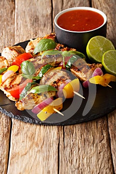 Delicious grilled chicken skewers with vegetables served with ketchup and lime close-up. vertical