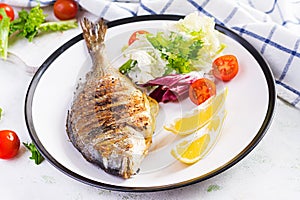 Delicious grilled dorado or sea bream fish with salad, spices, grilled dorada