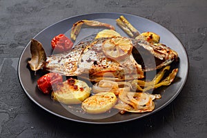 Delicious grilled dorado or sea bream fish with salad, spices, grilled dorada on a black plate. Top view, overhead, copy space