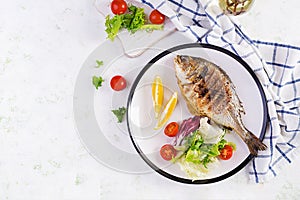 Delicious grilled dorado or sea bream fish with salad, spices, grilled dorada on a plate.