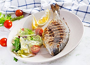 Delicious grilled dorado or sea bream fish with salad, spices, grilled dorada on a plateDelicious grilled dorado or sea bream fish