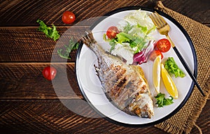 Delicious grilled dorado or sea bream fish with salad, spices, grilled doradaDelicious grilled dorado or sea bream fish with salad