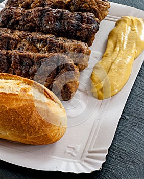 Delicious grilled minced meat rolls mici ori mititei traditional romanian and balkan dish served with mustard and bread on cardboa