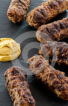 Delicious grilled minced meat rolls mici ori mititei traditional romanian and balkan dish served with mustard on a black slate