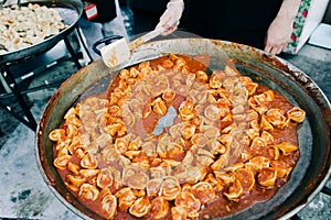 Delicious grilled ravioli in tomato sauce cooked in a large frying pan street food