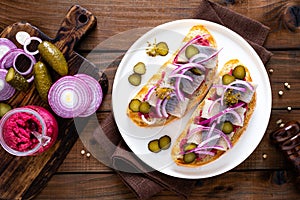 Delicious grilled sandwiches with herring, onion and beetroot sauce with horseradish on dark wooden rustic background. Danish cuis