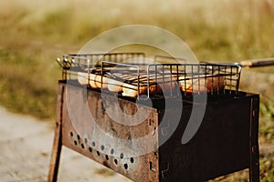 Delicious grilled sausages resting on the iron grid of a portable barbecue