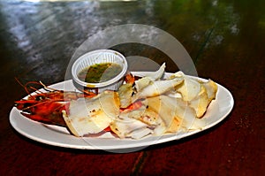 Delicious grilled seafood consists of grilled squid and grilled shrimp, along with a spicy dipping sauce.