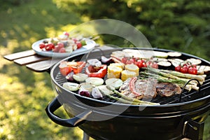 Delicious grilled vegetables and meat on barbecue grill outdoors, closeup
