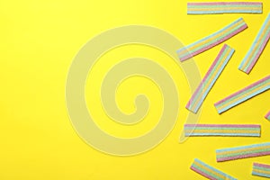 Delicious gummy candies on yellow background, flat lay. Space for text