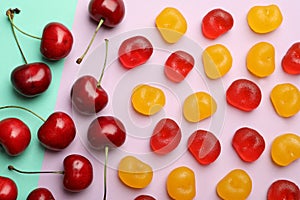 Delicious gummy cherry candies and fruits on color background, flat lay
