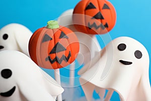 Delicious Halloween themed cake pops on blue background, closeup