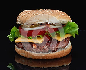 Delicious hamburger with beef with cheese, tomatoes, onions, cucumbers and tomatoes and ketchup on a black background and on a bla