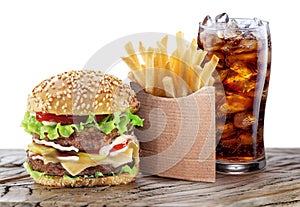 Delicious hamburger with cola and potato fries isolated on wooden table. Fast food concept