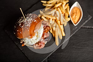 Delicious hamburger with french fries on dark background. Fast food