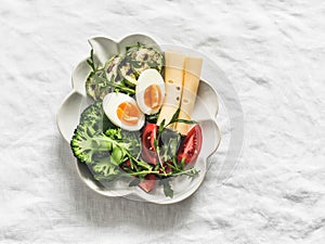 Delicious healthy breakfast, brunch, lunch - boiled egg, grilled zucchini, broccoli, arugula, tomatoes and cheese on a light