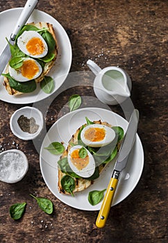 Delicious healthy breakfast - grilled bread sandwich with spinach and boiled eggs on wooden background