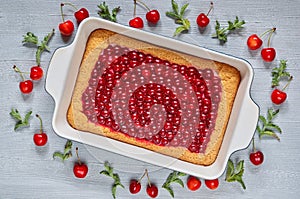 Delicious healthy dessert - cherry pie in the baking dish on the gray kitchen table. Cold summer tart decorated with cherry jelly
