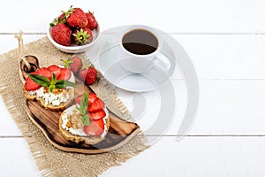 Delicious healthy dietary breakfast: rye bread with cottage cheese and strawberries and a cup of coffee espresso