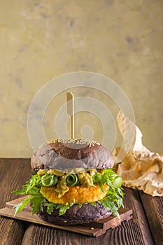 Delicious and healthy fast food. Vegetarian burger made from carrot patties on a wooden background.Lifestyle. Vertical position