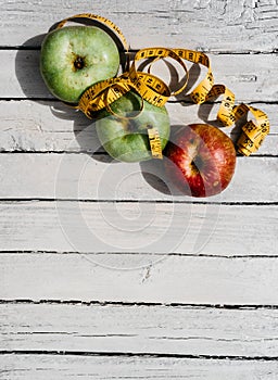 Delicious and healthy food is on the kitchen table. Three apples-yellow, green and red on a white wooden background and a yellow