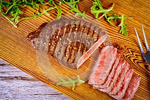 Delicious and healthy grilled medium rare beef steak on wooden board