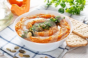 Delicious healthy homemade bean hummus with baked pumpkin, tahina and spices with flat bread on a light background