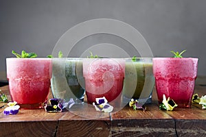 Delicious healthy kiwi and strawbeery, raspberry smoothies served with fresh mint in glasses on rustic wooden table.