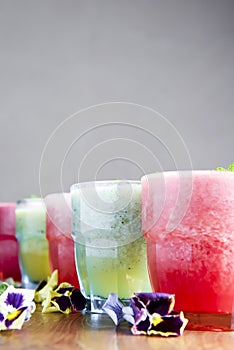 Delicious healthy kiwi and strawbeery, raspberry smoothies served with fresh mint in glasses on rustic wooden table.