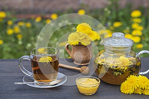 Delicious herbal tea made of fresh dandelion flowers with honey on wooden table in garden, close up