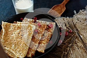 Delicious home-cooked food. Pancakes in a frying pan with cranberry berries and milk. Rustic style photo