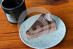 Delicious home made chocolate cake on plate and hot tea on wooden table