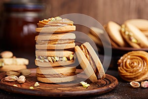 Delicious homemade alfajores cookies with milk caramel cream filling, decorated with pistachio nuts