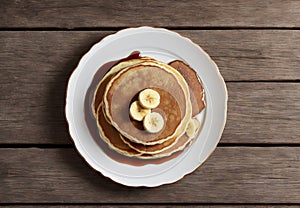 Delicious homemade banana pancakes with caramel on wooden table