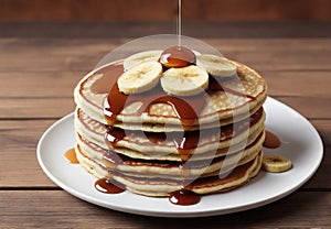 Delicious homemade banana pancakes with caramel on wooden table