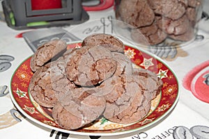 Delicious homemade cacao christmas cookies in a christmas plate and a jar and candle in the back