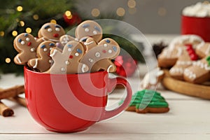 Delicious homemade Christmas cookies in cup on white wooden table against blurred festive lights. Space for text
